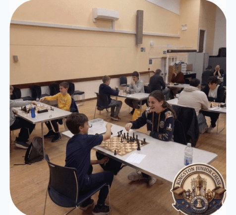Children and teenagers playing chess at multiple tables in a brightly lit community center hall.